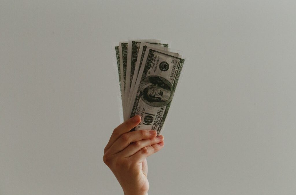 hand holding hundred dollar bills